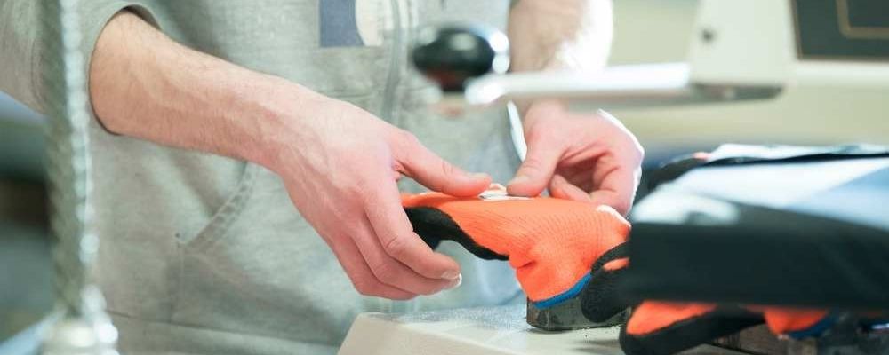 Majestic Glove employee applying a logo to safety gloves