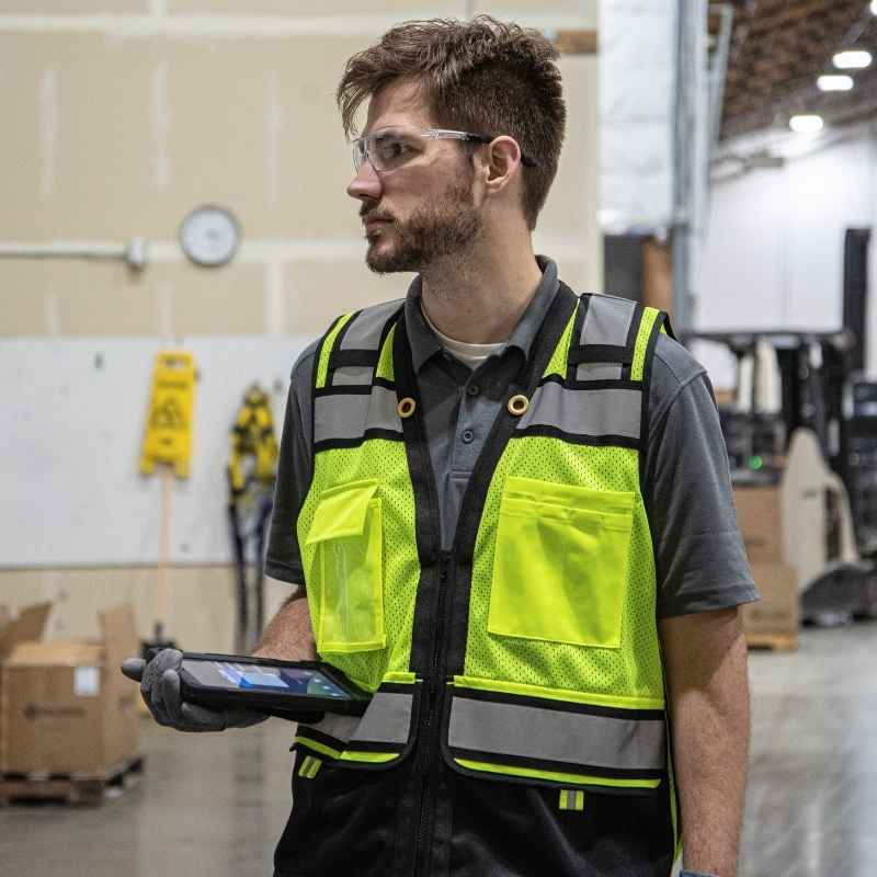 Worker holding a tablet wearing a high visibility vest.